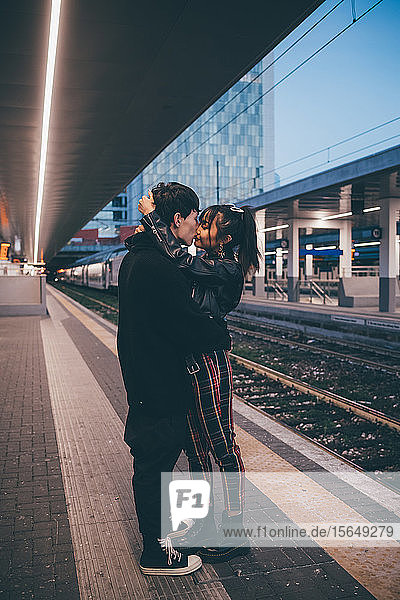 Junges Paar küsst sich auf dem Bahnsteig eines Bahnhofs  Mailand  Italien
