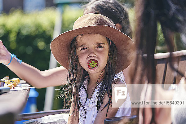Mädchen träumt mit Erdbeere im Mund
