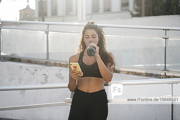 Junge Frau mit Smartphone im Stadtpark