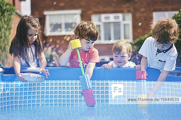 Kinder füllen Wasserpistole am Pool auf