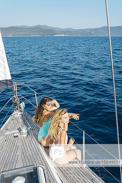 Friends relaxing on deck edge of sailboat  Italy