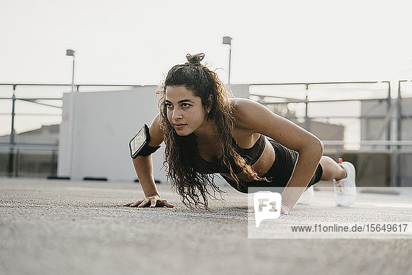 Young woman doing plank on rooftop deck