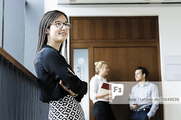 Young businesswoman in office  colleagues talking in background