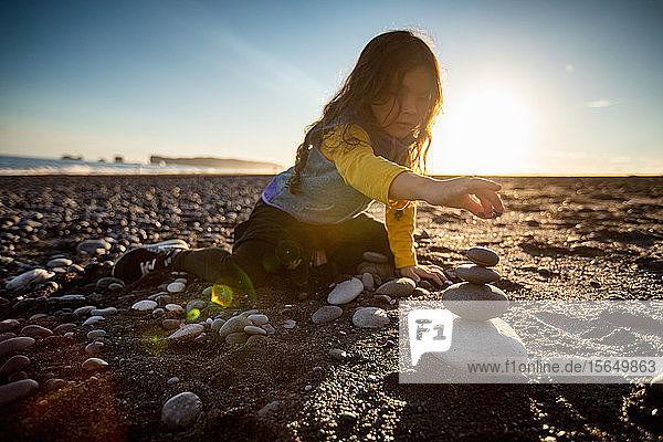 Kleines Mädchen stapelt Wunschsteine  schwarzer Sandstrand  Reynisfjara  Island