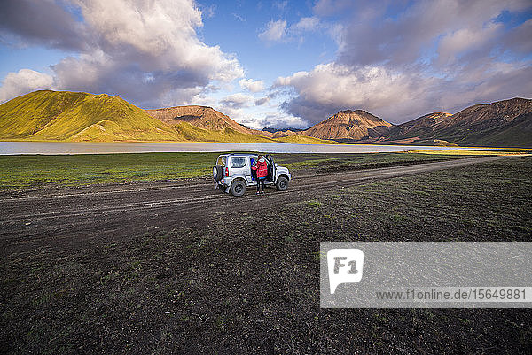 Reisende  die neben dem Fahrzeug eine malerische Aussicht genießt  Landmannalaugar  Hochland  Island