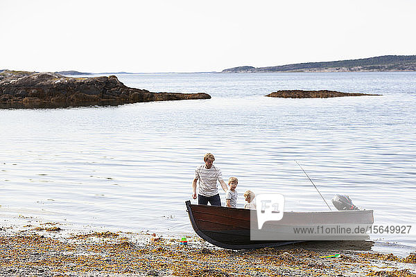 Vater und Söhne spielen neben dem am Strand vertäuten Boot  Norwegen