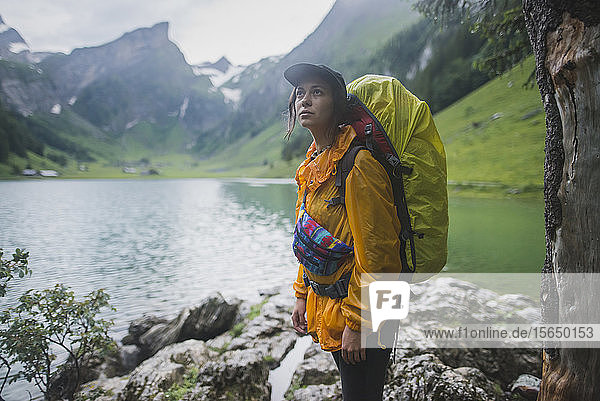 Woman wearing yellow backpack by Seealpsee lake in Appenzell Alps  Switzerland