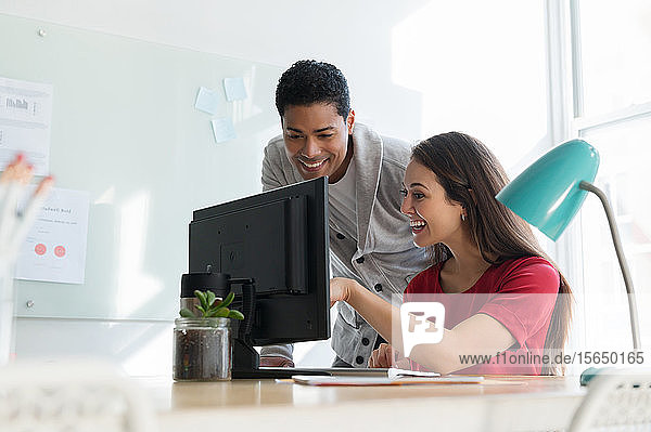 Coworkers smiling at computer together