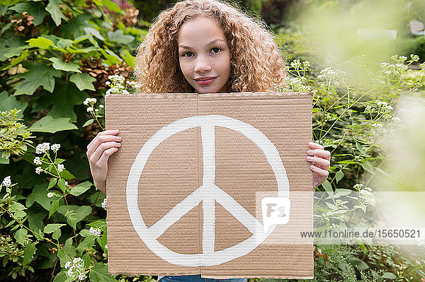 Mädchen hält Schild mit Friedenssymbol