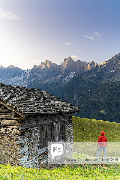 Rückansicht eines Mannes aus einer Steinhütte mit Blick auf den Piz Cengalo und Badile  Tombal  Bergell  Kanton Graubünden  Schweiz