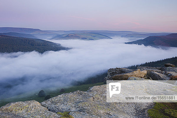 Die Morgendämmerung bricht über den Hügeln des Peak District mit einer Wolkeninversion über dem Ladybower Reservoir unterhalb von Bamford Edge  Peak District  Derbyshire  England  Vereinigtes Königreich