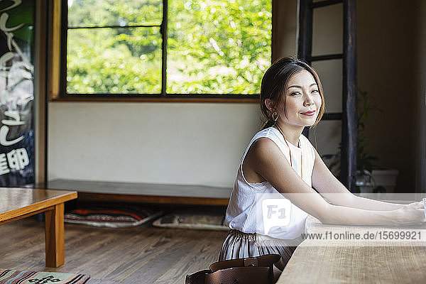 Lächelnde Japanerin  die an einem Tisch in einem japanischen Restaurant sitzt.