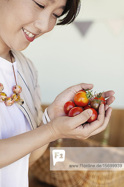 Nahaufnahme einer Japanerin  die frisch gepflückte Tomaten hält.