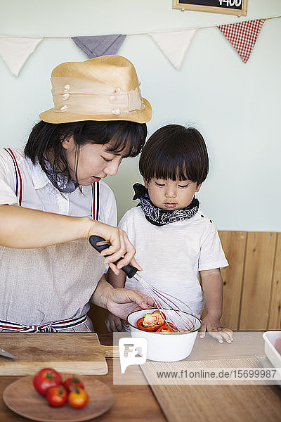 Japanische Frau und Junge stehen in einem Hofladen und bereiten Essen vor.