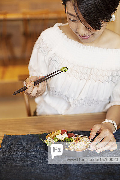 Japanische Frauen essen mit Stäbchen in einem vegetarischen Café.