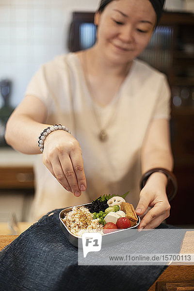 Japanerin  die in einem vegetarischen Café frisches Gemüse zubereitet.
