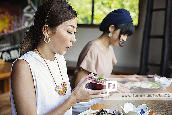Zwei Japanerinnen sitzen an einem Tisch in einem japanischen Restaurant und essen.
