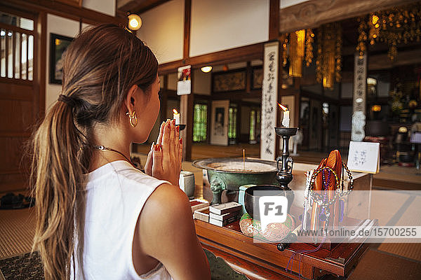 Zwei Japanerinnen knien im buddhistischen Tempel und beten.