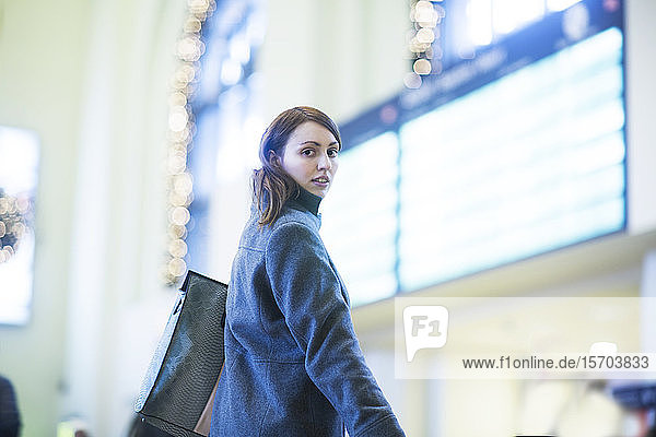 Junge Frau vor der digitalen Tafel im Zugterminal