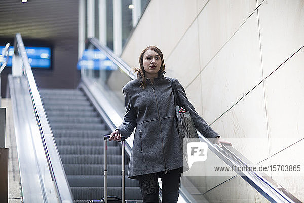 Junge Frau auf Rolltreppe im Zugbahnhof
