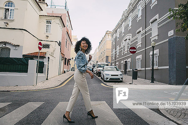Porträt glückliche  stilvolle Frau beim Überqueren der Stadtstraße