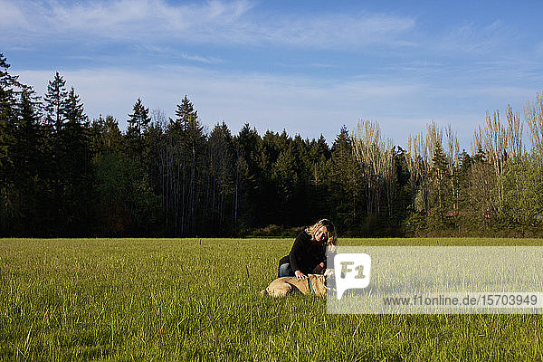 Frau mit Hund in einem sonnigen  ländlichen Feld