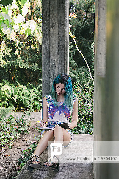Junge Frau schreibt im Park in ein Tagebuch