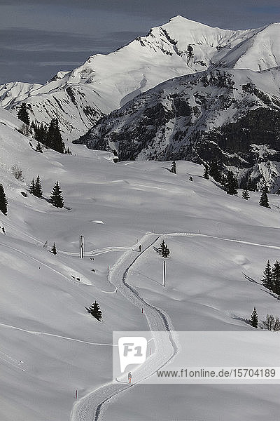 Schneeschuhläufer auf sonnigem  verschneitem Bergweg  Vals  Kanton Graubünden  Schweiz