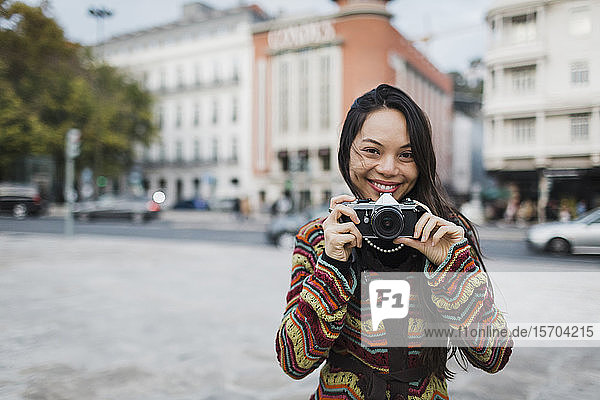 Porträt einer selbstbewussten  unbekümmerten Touristin mit Kamera auf einer Straße in der Stadt