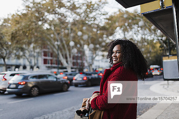 Lächelnde junge Frau auf städtischem Bürgersteig