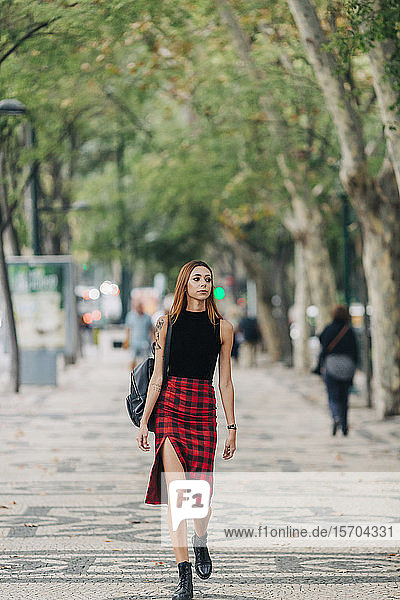 Stilvolle junge Frau geht im Stadtpark spazieren