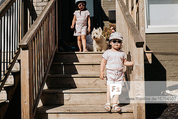 Sisters coming down stairway of house