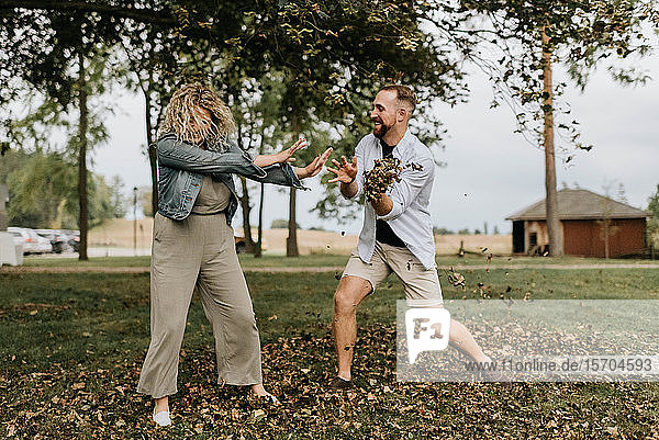Young man throwing leaves playfully at woman in countryside