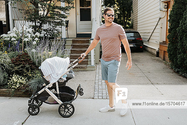 Father pushing baby carriage on pavement