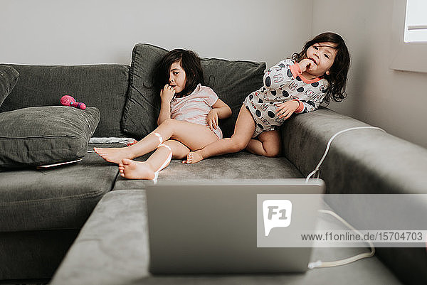 Schwestern entspannen sich vor dem Laptop auf der Couch