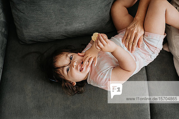 Kleinkind hält Cracker entspannt auf der Couch