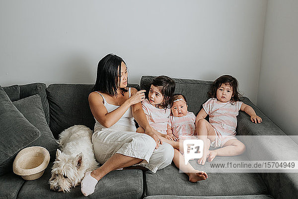 Mother and daughters relaxing on couch in living room