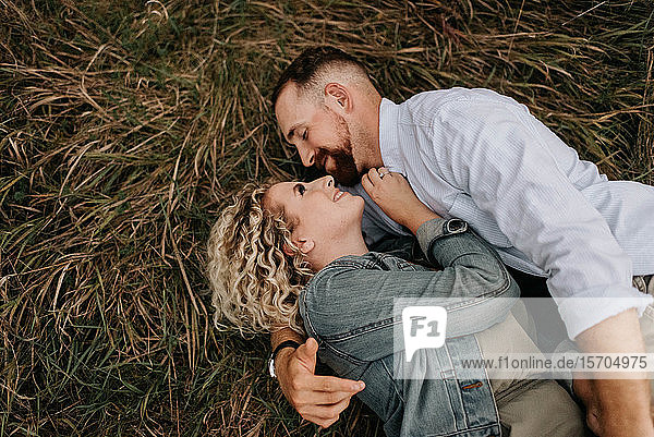 Junges Paar umarmt sich auf braunem Gras