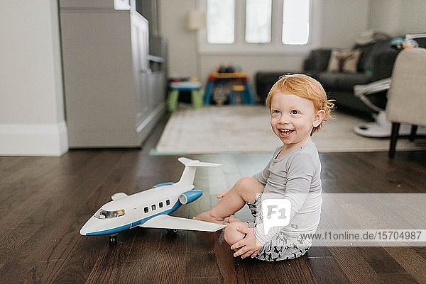 Toddler playing with toy aeroplane in living room