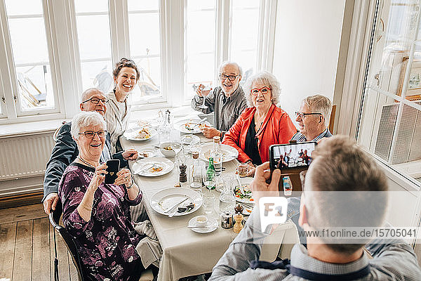 Kellner klickt Foto von älteren Freunden  die im Restaurant sitzen
