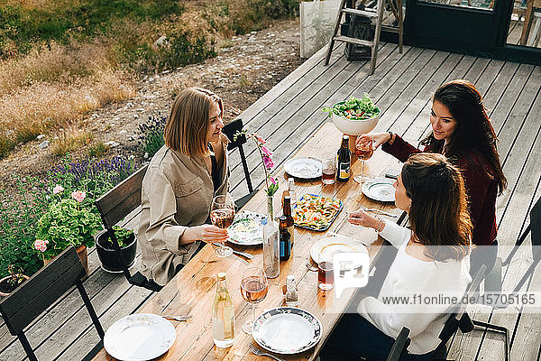 Schrägaufnahme von Freundinnen  die sich beim Essen im Vorgarten unterhalten