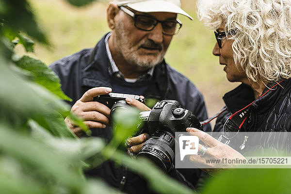Ältere Frau spricht  während sie während eines Fotokurses einem Freund die Kamera zeigt