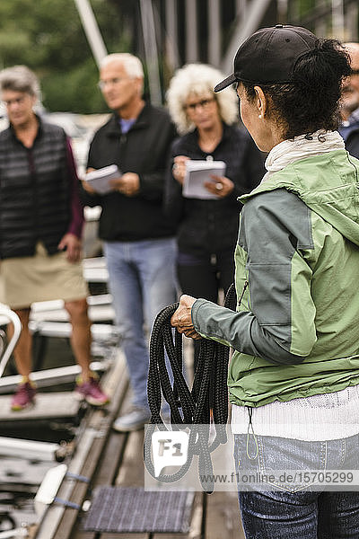 Weibliche Ausbilderin hält Seil  während sie ältere Männer und Frauen im Bootsführerkurs unterrichtet
