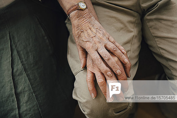Mittelteil eines älteren Ehepaares im Ruhestand  das im Pflegeheim sitzend Händchen hält