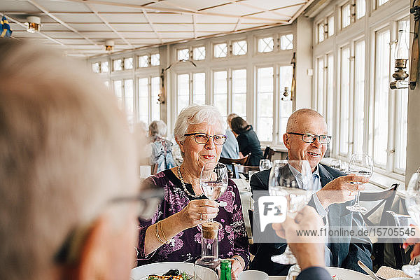 Senior friends with wineglass toasting in restaurant