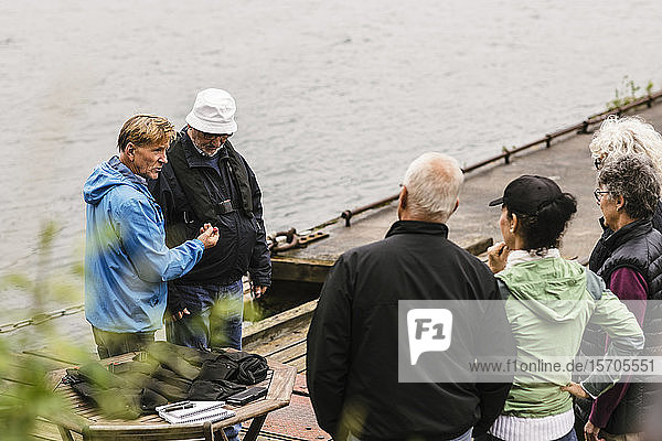 Ältere Männer und Frauen hören dem männlichen Ausbilder während des Bootsführerkurses am Pier zu