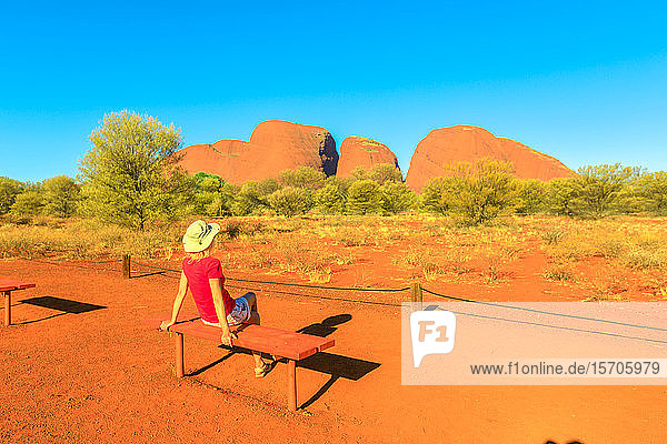 Touristin  die sich auf einer Bank ausruht und die leuchtenden Farben der kuppelförmigen Felsformationen im Kata Tjuta Sunset Viewing Area bewundert  Uluru-Kata Tjuta National Park  UNESCO World Heritage Site  Northern Territory  Australien  Pazifik