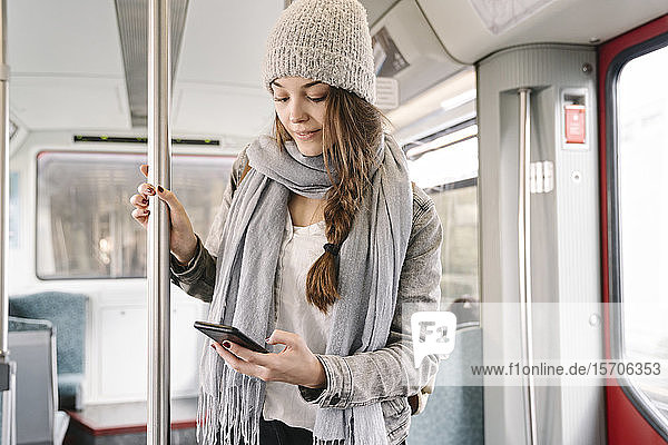 Junge Frau mit Smartphone in der U-Bahn