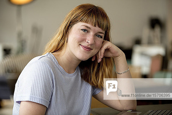 Porträt einer erdbeerblonden jungen Frau mit Nasenpiercing in einem Café