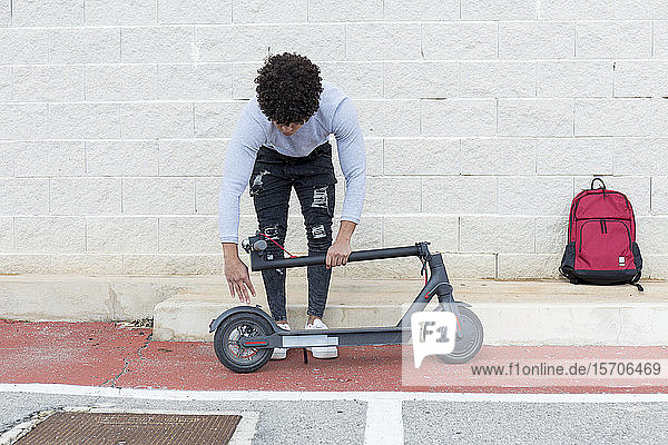 Young man folding e-scooter